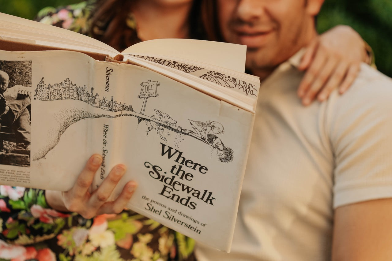 Holding the book "Where the sidewalk ends" a man and woman couple read it together